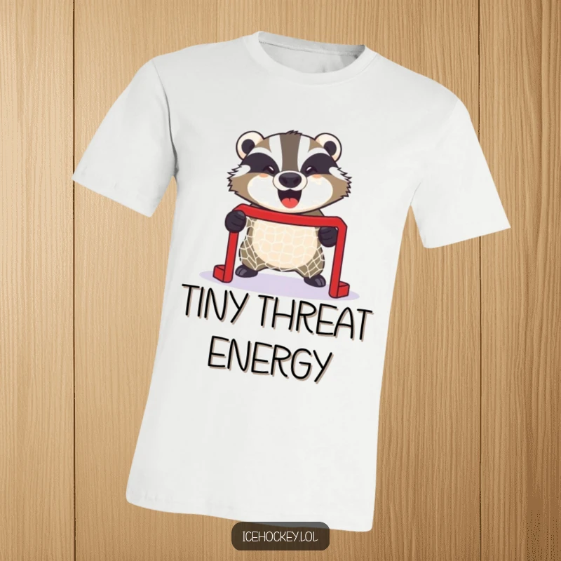 Funny t-shirt of a giggling badger fiercely defending a miniature hockey net, showcasing intense goalie focus with a smile.